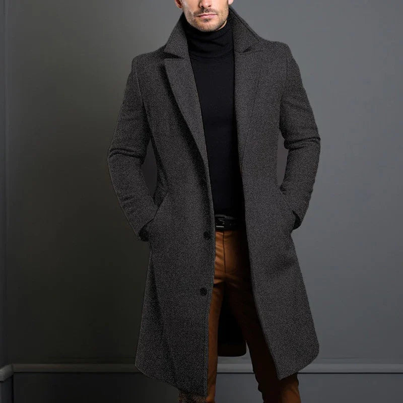 Man wearing grey wool overcoat, black turtleneck, and brown pants, modern minimalist style