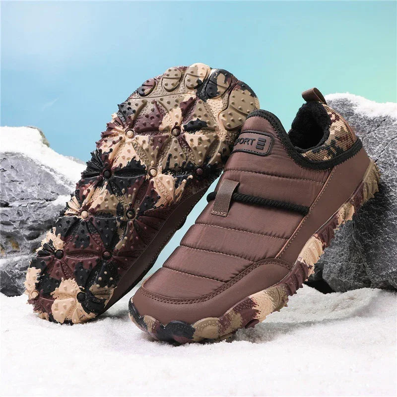 Brown insulated slip-on winter shoes with rugged soles on snowy ground.